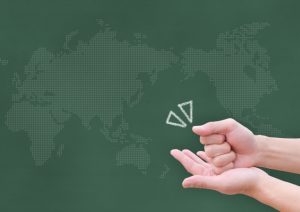 世界地図を背景に納得したように手をポンと打つ画像